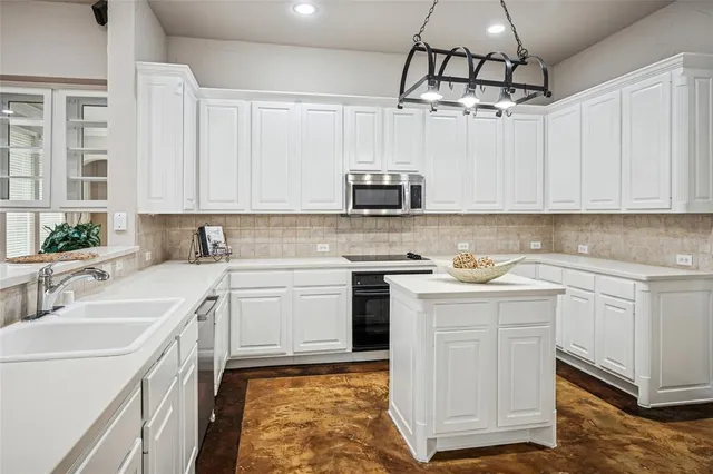 a kitchen with kitchen island granite countertop a sink stove and white cabinets