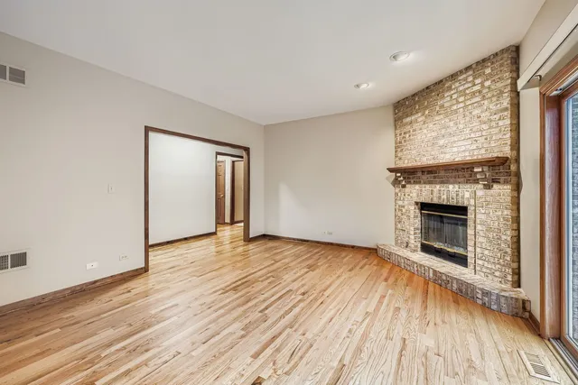 an empty room with wooden floor fireplace and windows