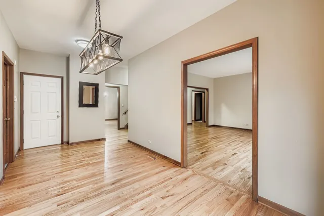 a view of a hallway with wooden floor and a refrigerator