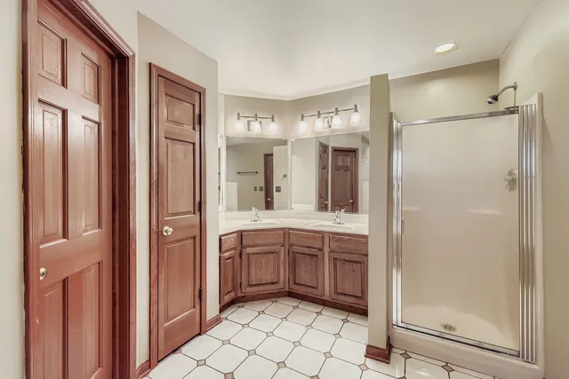 a bathroom with a double vanity sink mirror and shower