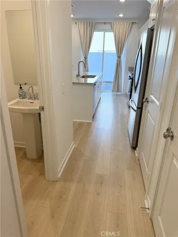 a view of a hallway with wooden floor and a bathroom