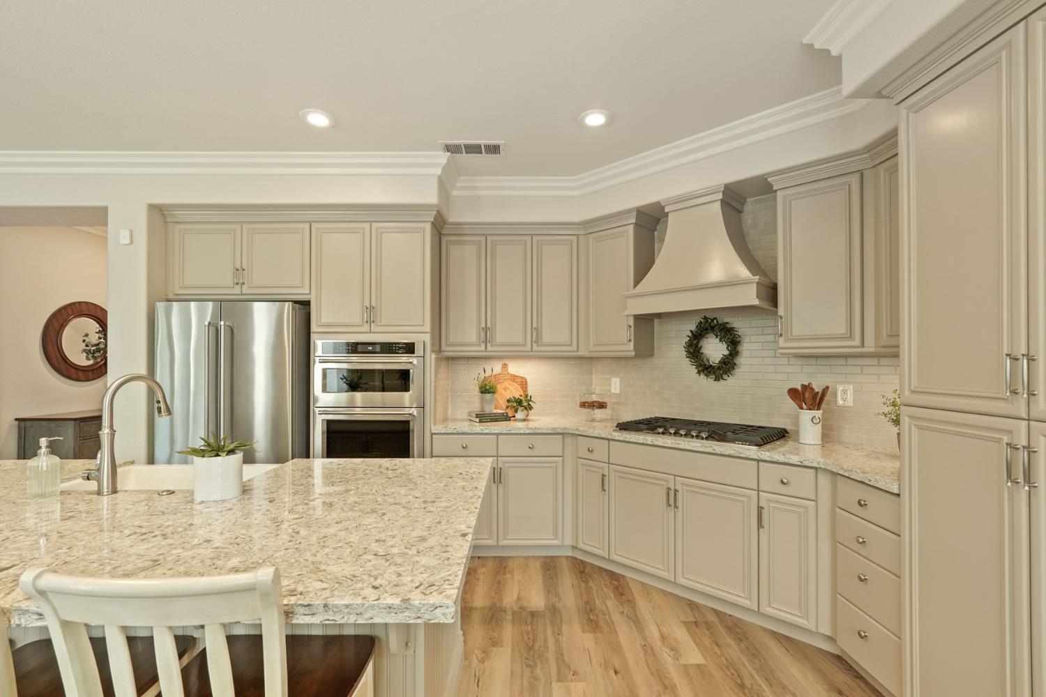 2227 Heavenly Way Lodi, CA 95242 - Photo 26 of 62 a kitchen with kitchen island granite countertop a stove a sink a refrigerator and white cabinets with wooden floor
