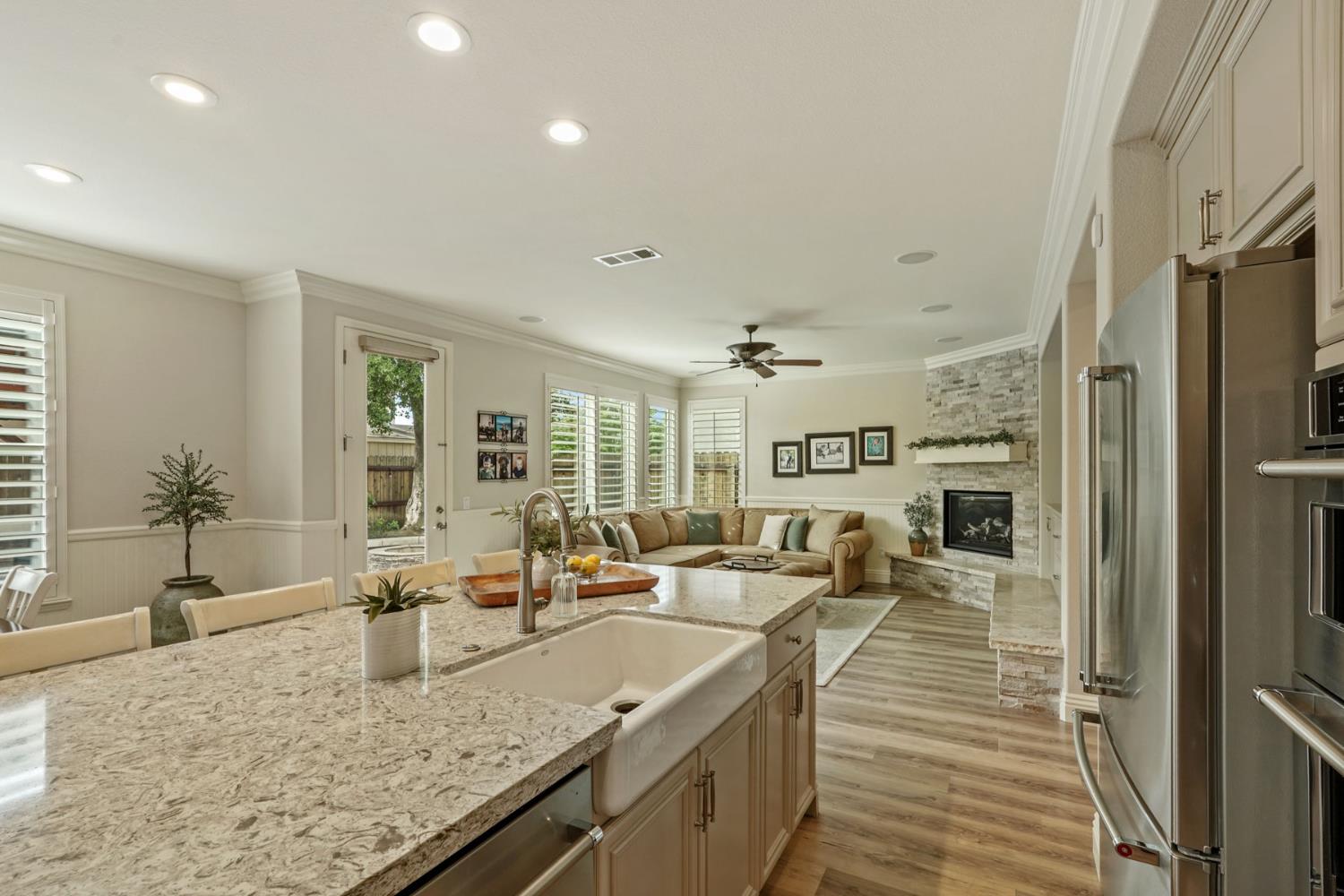 2227 Heavenly Way Lodi, CA 95242 - Photo 27 of 62 a large living room with stainless steel appliances granite countertop couches a fireplace and a large window with wooden floor