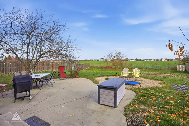 a patio with table and chairs and potted plants with wooden floor and fence