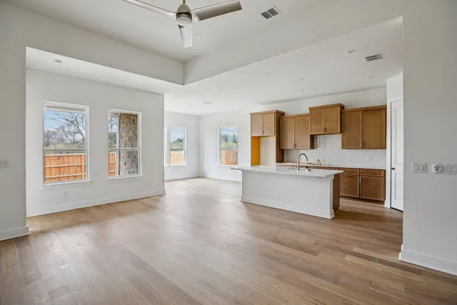 a large kitchen with stainless steel appliances kitchen island a large counter top and a wooden floors