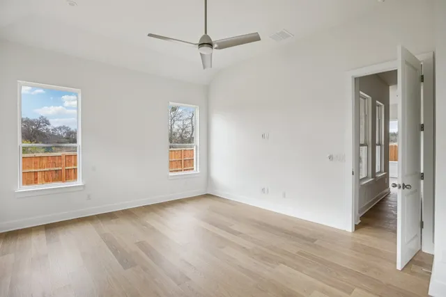 a view of empty room with wooden floor and fan