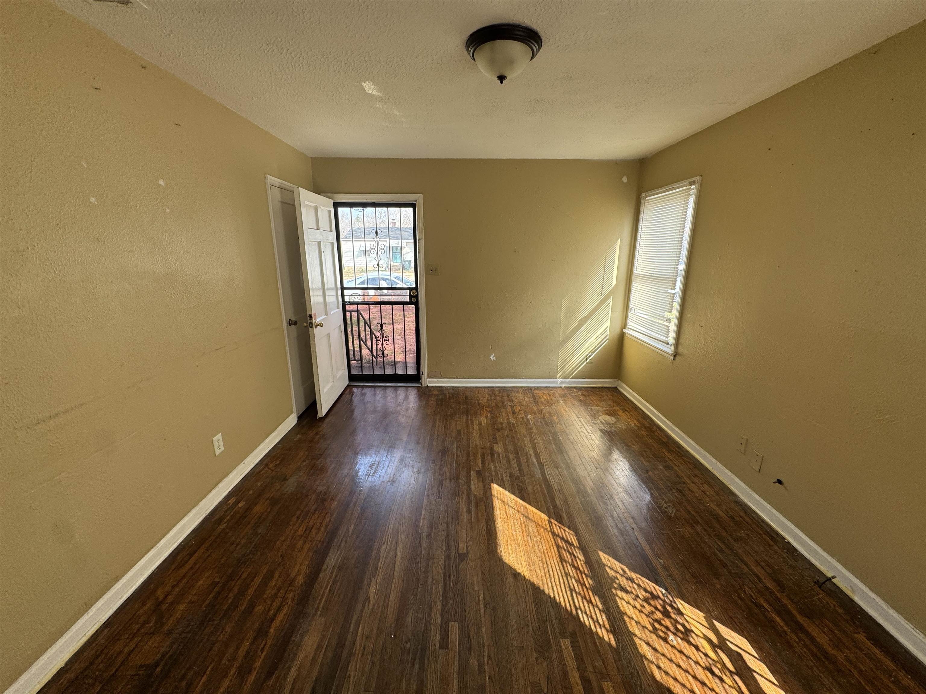 4071 Grey Road Memphis, TN 38108 - Photo 4 of 8 Empty room with dark wood-style flooring, a textured wall, and a textured ceiling