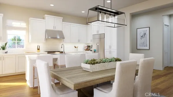 a kitchen with stainless steel appliances granite countertop a table chairs and a refrigerator