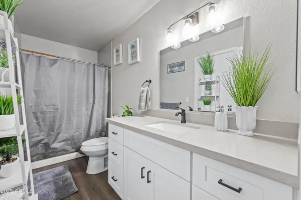 a bathroom with a granite countertop sink a toilet a mirror and shower