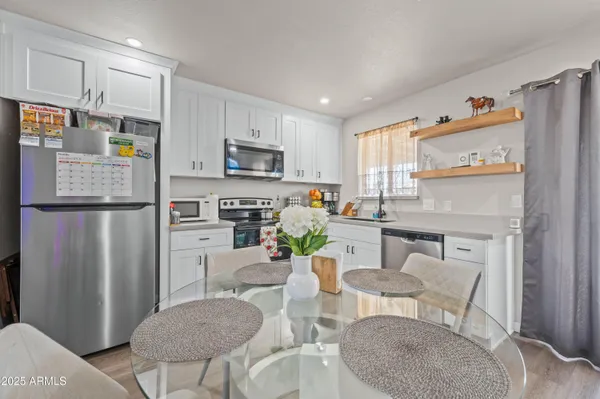 a kitchen with stainless steel appliances granite countertop a refrigerator a stove a sink and chairs