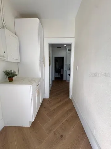 a view of a hallway with wooden floor and cabinets