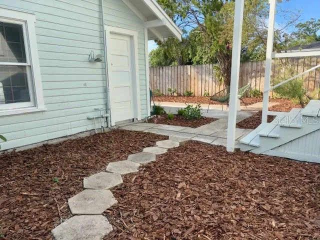 a view of a backyard with a large tree and wooden fence