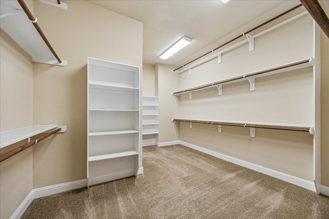 14123 Spindle Arbor Road Cypress, TX 77429 - Photo 21 of 45 Oversized walk-in closet serves the primary bedroom. Closet features multiple shelves and wooden rods for ample storage and organization. Bright lighting. Access to utility room.
