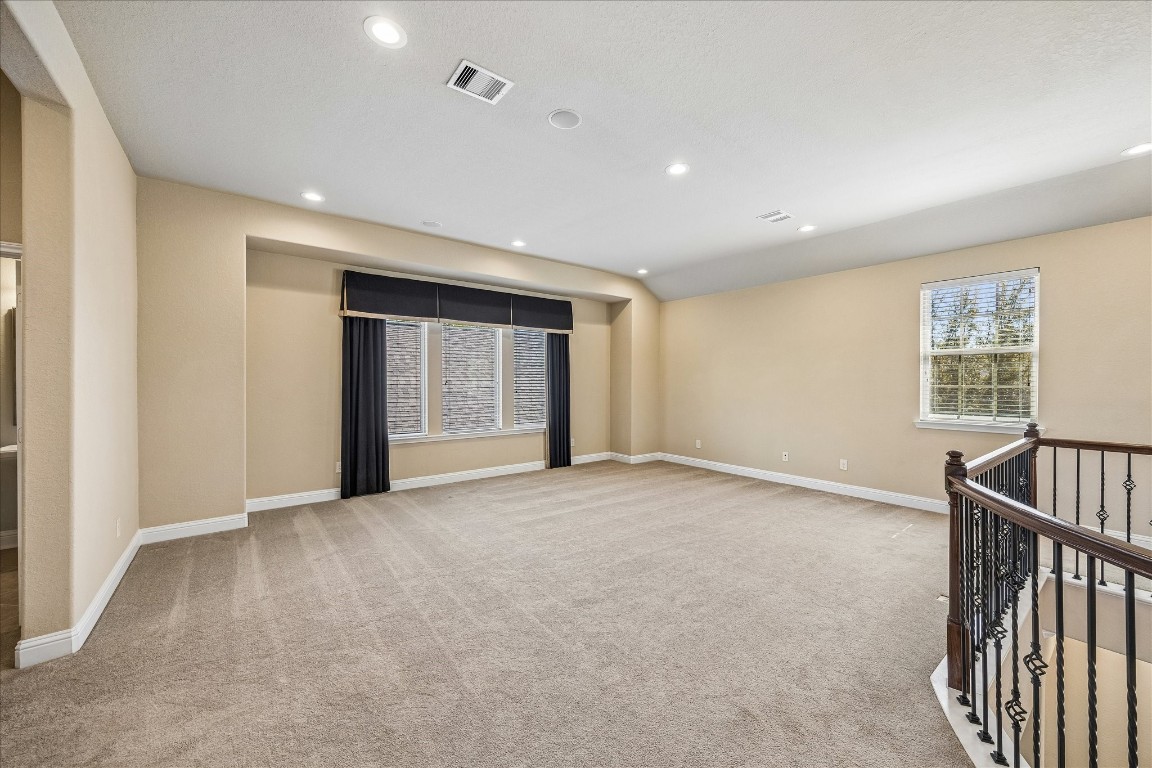 14123 Spindle Arbor Road Cypress, TX 77429 - Photo 27 of 45 Game room features neutral walls and natural light provided by large windows. It includes recessed lighting and an elegant staircase with wrought iron railing, offering a versatile and inviting space.