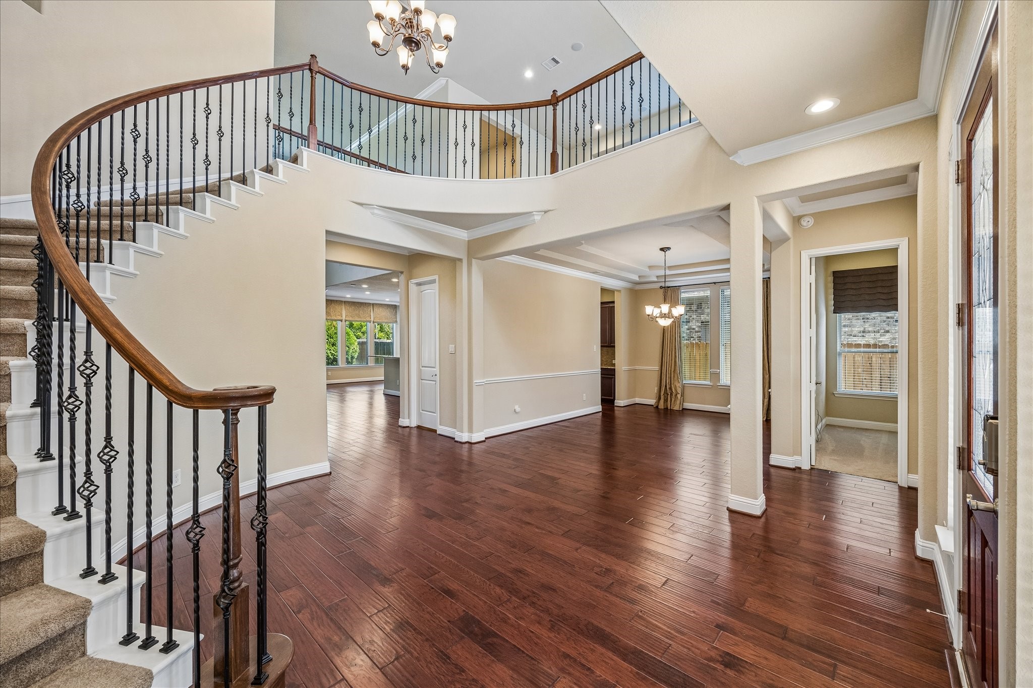 14123 Spindle Arbor Road Cypress, TX 77429 - Photo 3 of 45 Spacious and elegant entryway with a grand curved staircase and rich hardwood floors. The open layout features high ceilings and ample natural light, leading into a formal dining area and guest room.