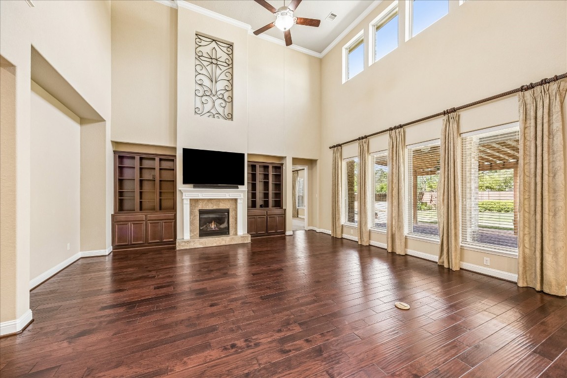 14123 Spindle Arbor Road Cypress, TX 77429 - Photo 6 of 45 The expansive family room features high ceilings, hardwood floors, and abundant natural light. It includes a gas log fireplace, built-in bookshelves, and art niche.