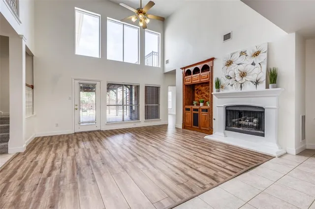 a view of an empty room with wooden floor fireplace and a window