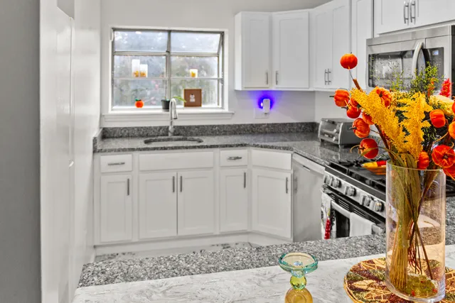 a kitchen with white cabinets and sink