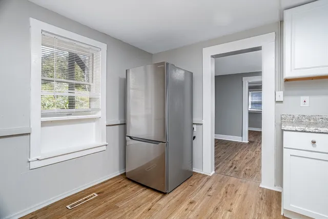 a kitchen with white cabinets and wooden floor