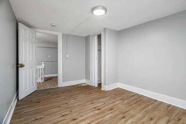 a view of empty room with wooden floor and bathroom