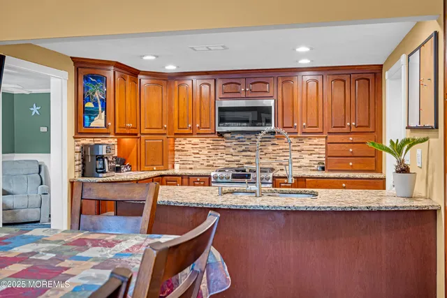 a kitchen with stainless steel appliances granite countertop a stove a sink and a microwave