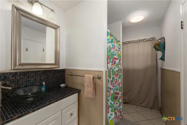 a bathroom with a granite countertop shower a sink and a mirror