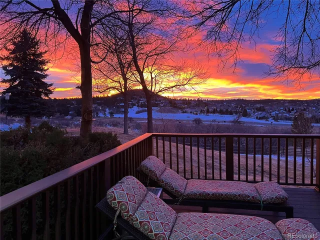 a view of a roof deck with couches and wooden fence