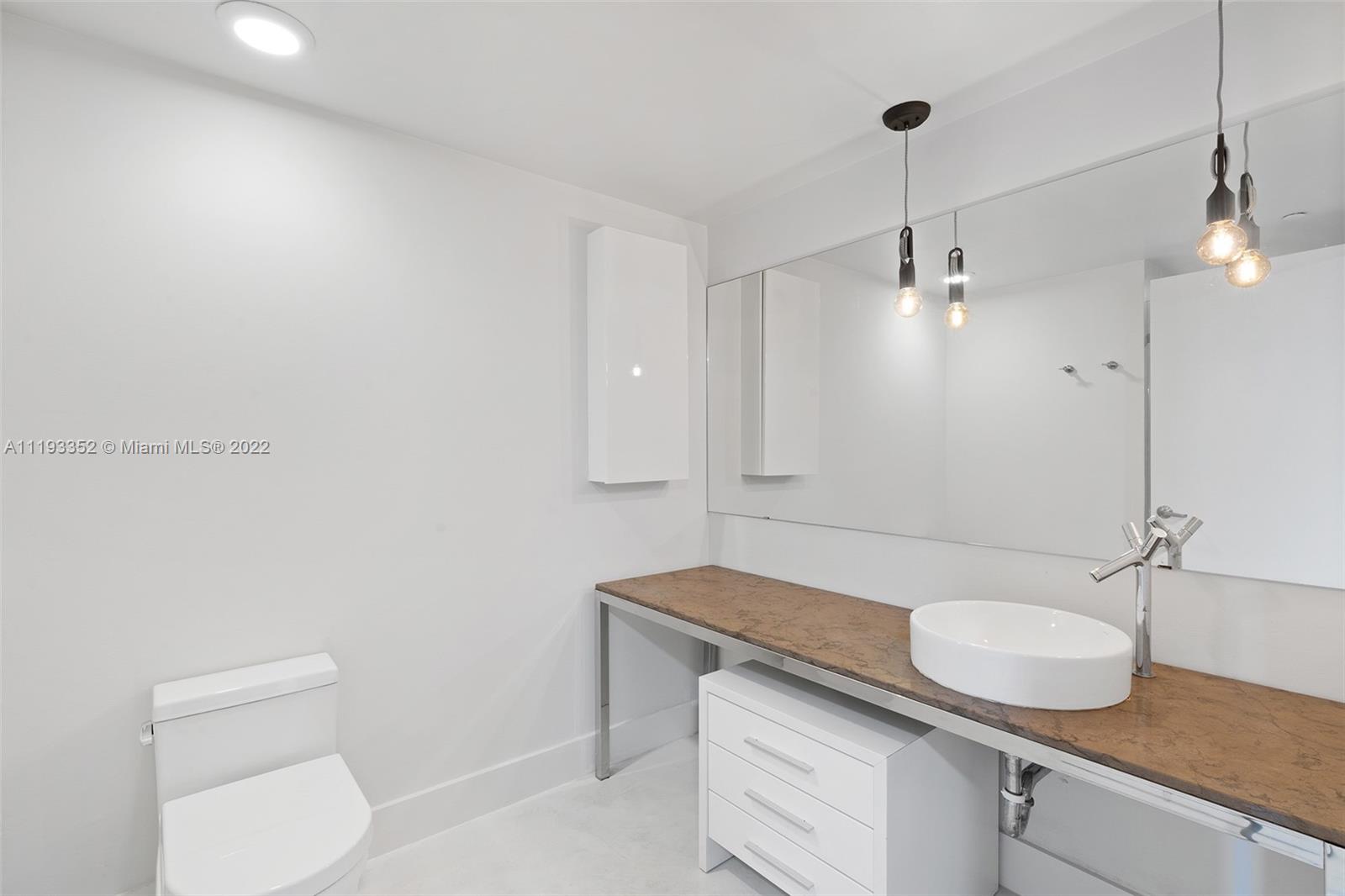 465 Brickell Avenue, Unit 2604 Miami, FL 33131 - Photo 14 of 23 a bathroom with a granite countertop sink a toilet a mirror and vanity
