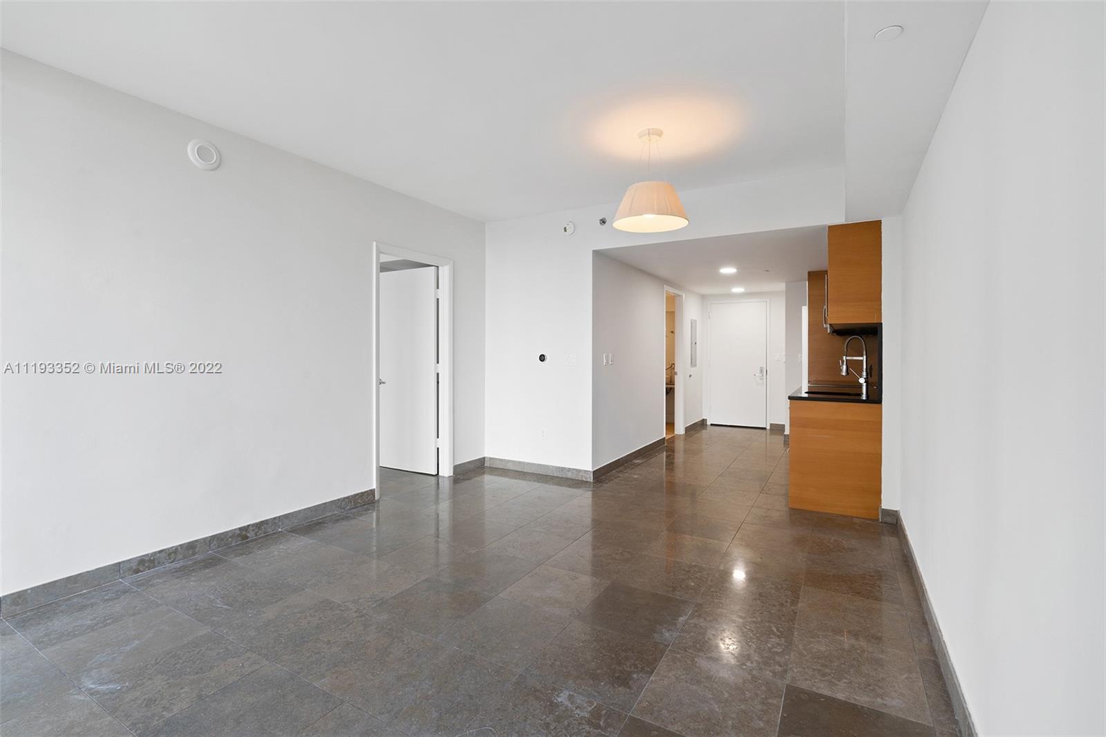 465 Brickell Avenue, Unit 2604 Miami, FL 33131 - Photo 7 of 23 a view of an empty room with wooden floor and a kitchen