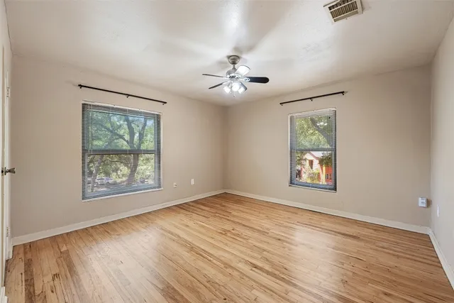 a view of an empty room with a window and wooden floor