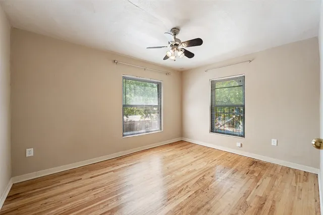 a view of an empty room with a window and wooden floor