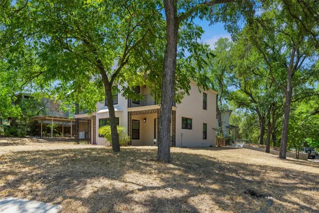 a view of a house with a yard and large tree