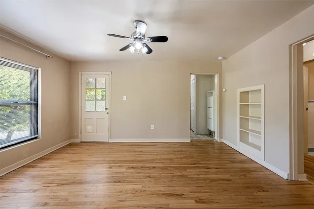 a view of an empty room with wooden floor and a window