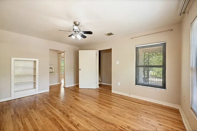 a view of an empty room with window and wooden floor