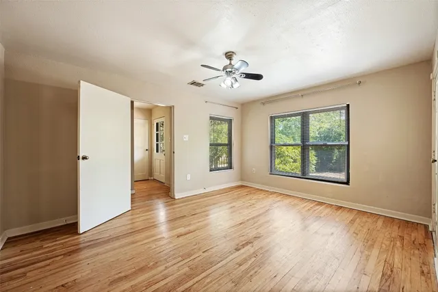 a view of an empty room with a window and wooden floor