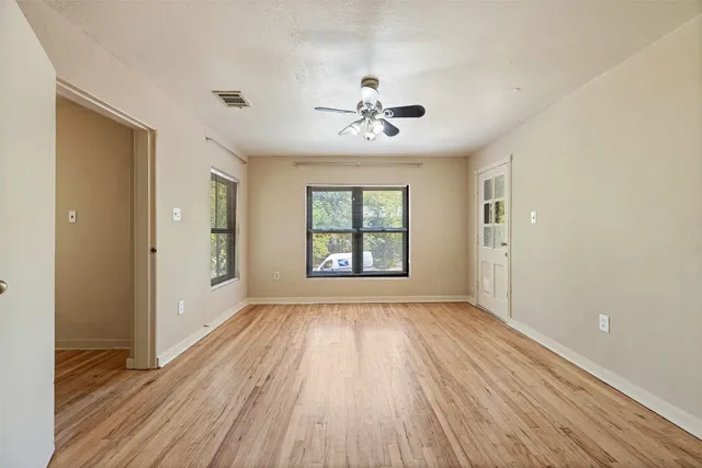 a view of an empty room with wooden floor and a window