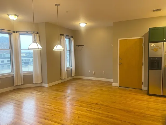 a view of an empty room with window and wooden floor