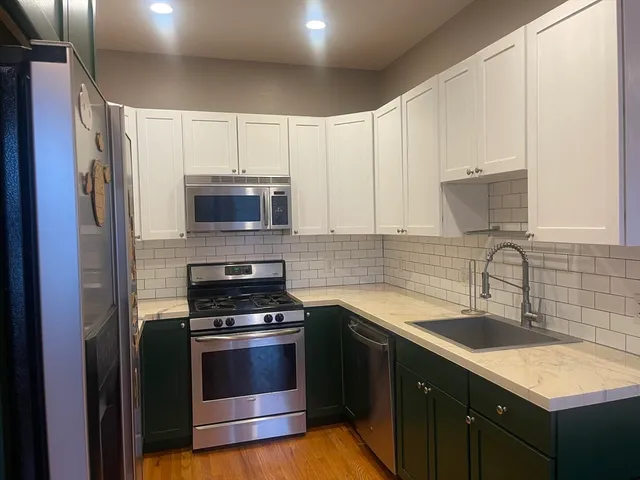 a kitchen with granite countertop a sink cabinets and stainless steel appliances