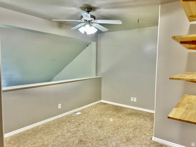 672 West 720 South Logan, UT 84321 - Photo 8 of 15 Carpeted room featuring a ceiling fan with integrated lighting, a half-wall partition, and built-in wood-finish shelving