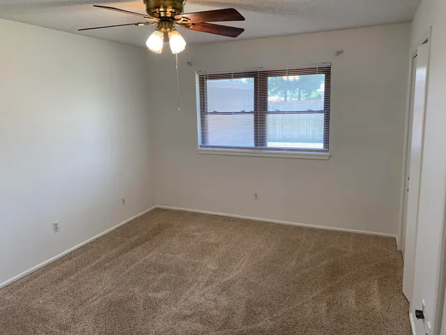 an empty room with a window and a chandelier fan