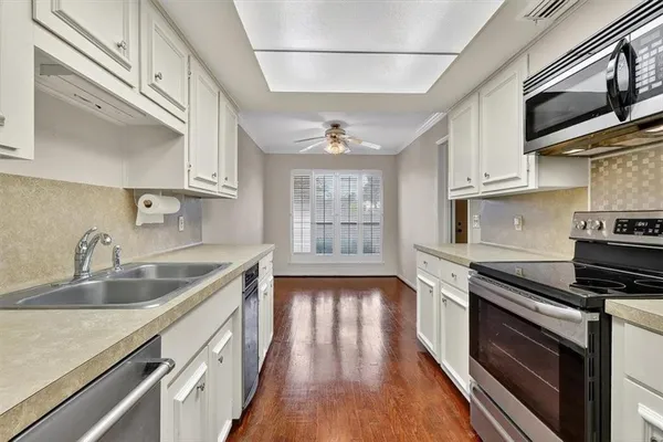 a kitchen with stainless steel appliances white cabinets and wooden floors