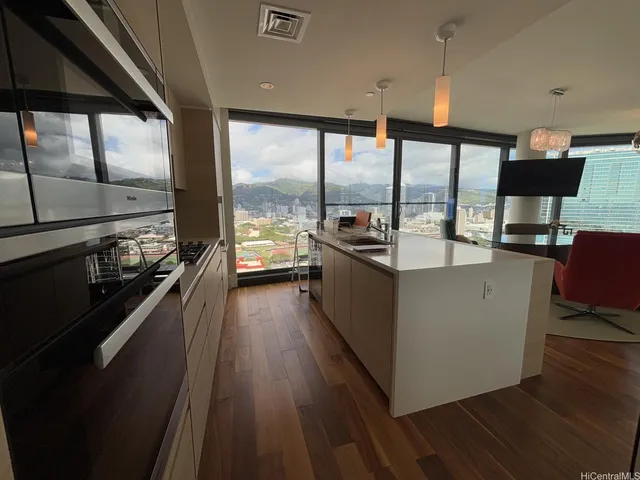 a living room with stainless steel appliances kitchen island granite countertop a large kitchen counter top a stove and a wooden floors