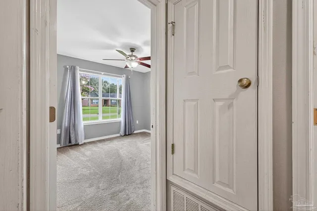 an empty room with ceiling fan and windows