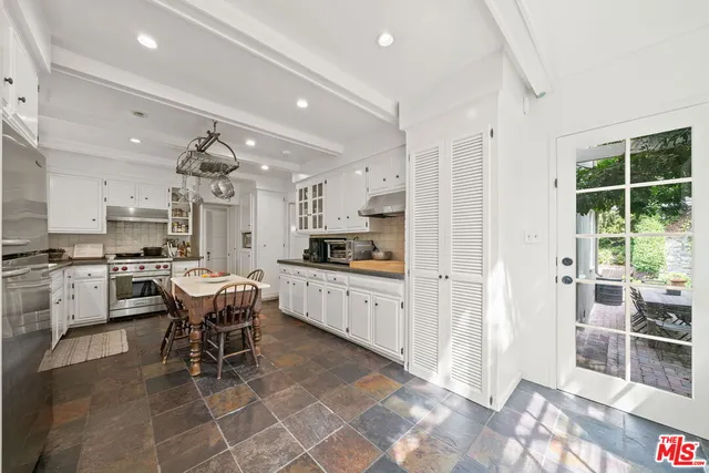 a kitchen with stainless steel appliances kitchen island granite countertop a refrigerator a stove a dining table and chairs with wooden floor