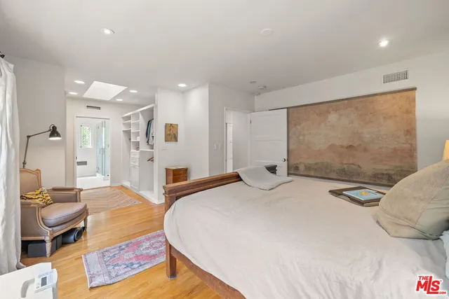 a spacious bedroom with a bed a couch and a flat tv screen on the table