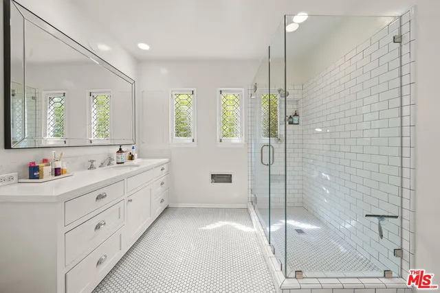a bathroom with a double vanity sink mirror and shower