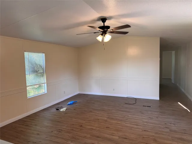 an empty room with wooden floor fan and windows