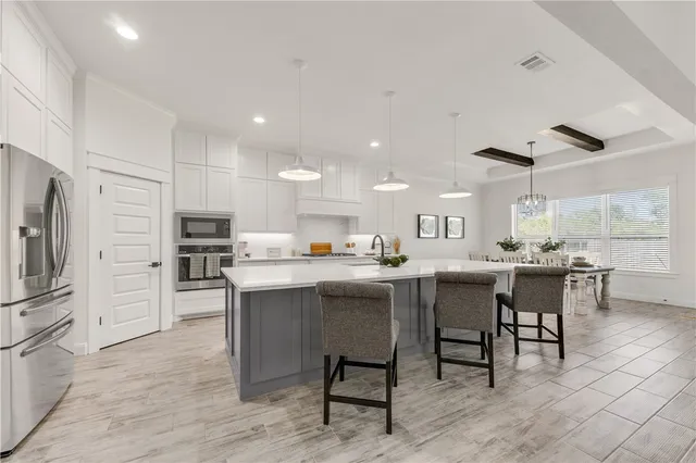 a kitchen with stainless steel appliances kitchen island granite countertop a table chairs sink and cabinets