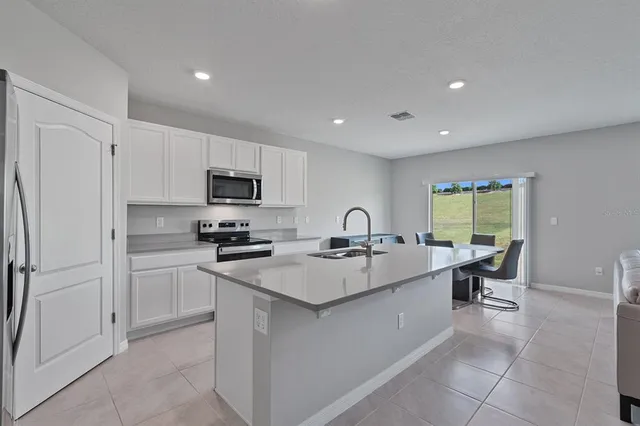 a large kitchen with a sink stainless steel appliances and cabinets