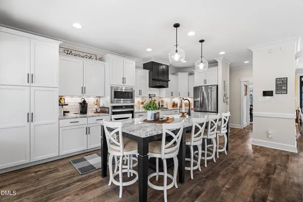 a kitchen with stainless steel appliances kitchen island granite countertop a table chairs and a refrigerator